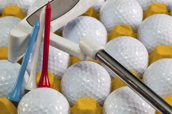 White golf balls in the yellow box and golf equipments