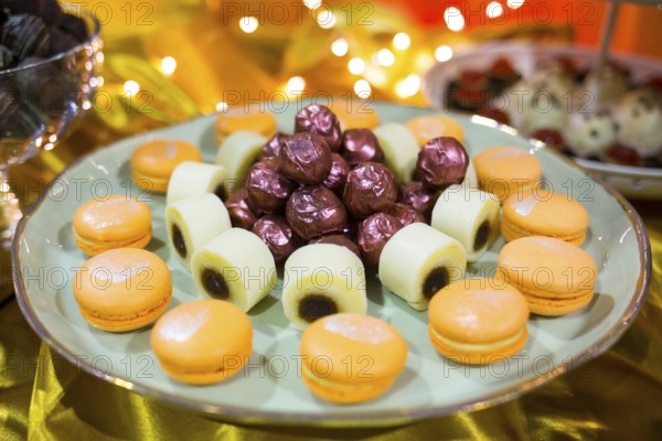 Circular cake macaron or macaroon is a sweet meringue-based confection. Extremely tasty and delicious desserts. Sweets full with sugar. Unhealthy food diet. In a plate with purple wrapped bonbons