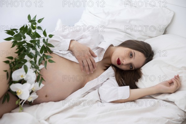 A serene maternity pose featuring natural elements and soft bedding, celebrating the essence of motherhood