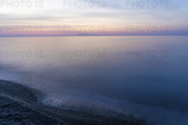 Dawn, cloudy mood in front of sunrise, view from the lava beach to the island of Anafi, long exposure, Kamari, island of Santorini, Cyclades, Greece, Europe
