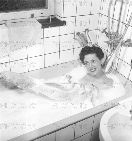 Having a bath 1950. A young smiling woman wearing a princess crown, is having a bath in a bathtub at home. Sweden 1952 Photo Kristoffersson ref BK4-5