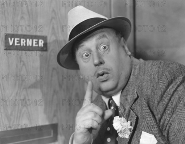 Secretive in the 1940s. Actor Thor Modéen pictured while acting in the movie Tåget går klockan 9. Making the sign with his finger, perhaps to silence someone and to be able to listen to what they are saying on the other side of the door he stands in front of. Sweden 1941