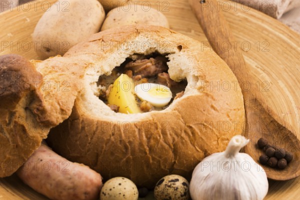Traditional white borscht (zurek) with sausage, egg and mushrooms in bread as bowl