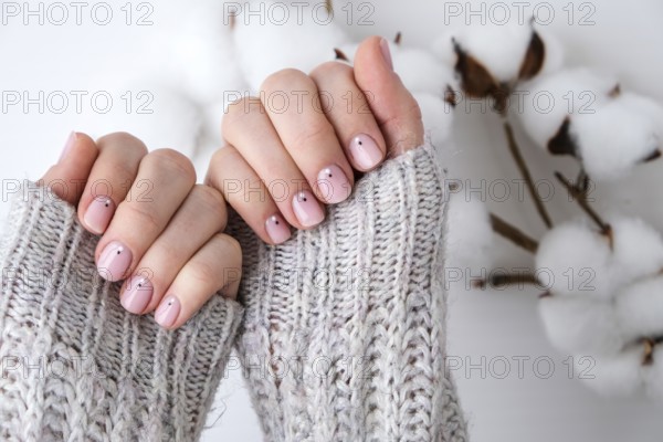 Woman hands with beautiful nude manicure holding delicate white cotton flower. Female Manicure, natural look. Nails care. Self care. SPA and beauty concept