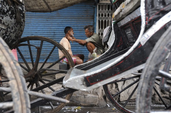 20.02.2011, Kolkata, West Bengal, India, Asia, A man gets a shave between rickshaws on a roadside in Kolkata, the only city in India where hand-pulled rickshaws still exist, Asia