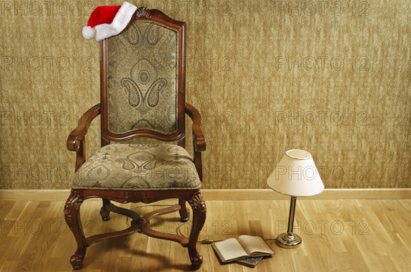 Old armchair with Santa hat and a lamp with a book near it