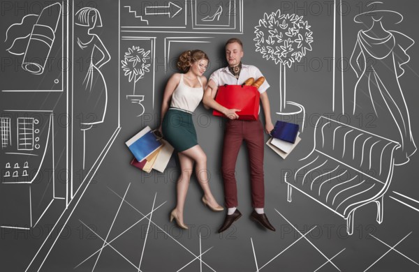 Love story concept of romantic couple shopping against chalk drawings background. Young happy couple standing together with shopping bags in a shopping centre