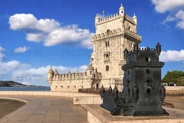 Belem tower and its scale model, Lisbon, Portugal at blue summer day sky with clouds. Medieval fort on Tagus river in late Gothic or Manueline style, UNESCO world heritage site, Age of Discoveries, tourist attraction, Portuguese seafaring history