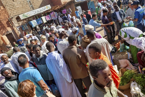 Large crowds at a lively market, surrounded by stalls and lively exchanges, The marketplace of Timimoun in the Sahara in Algeria
