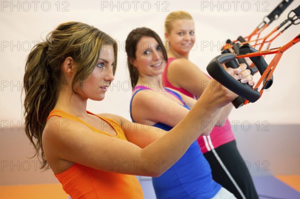 Young woman doing suspension training at the health club