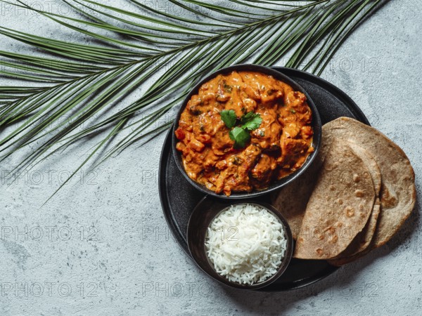 Indian cuisine dishes: tikka masala, rice, samosa, chapati, . Indian food on gray stone background with copy space. Assortment indian meal top view or flat lay
