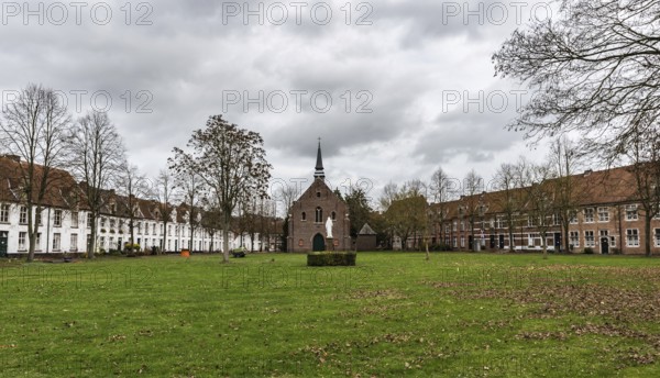 Belgium, 12 08 2018: Old houses and a chapel at the beguinage with bare trees and a meadow during winter, Europe
