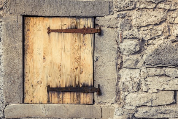 Rustic architecture background with a stone wall of a german house, with it's wooden trap door and the rusty hinges