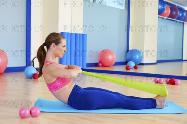 Pilates woman rowing rubber band exercise workout at gym indoor