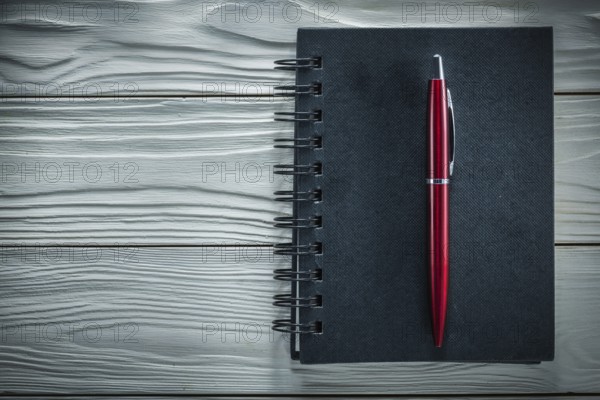 Black notepad pen on a white wooden board