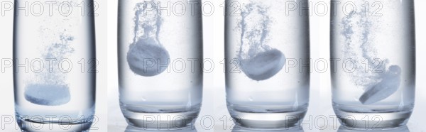 Tablets Falling and Dissolving into a Glass of Water against White Background