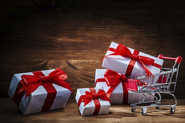 Set of white gift boxes with shopping trolley on vintage wood