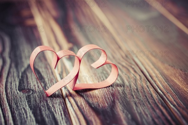 Two paper hearts on wooden background in vintage look - soft focus. Symbol of love. Space for text