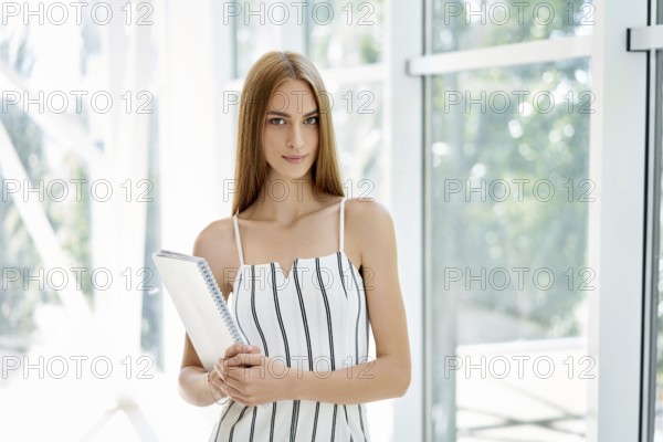 Confident business woman holding documents and looking at camera in modern creative office