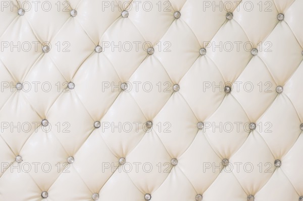 Beige soft tapestry pattern background with symmetrical buttons on the corners of diamonds. Soft and expensive furniture elements. Luxury background