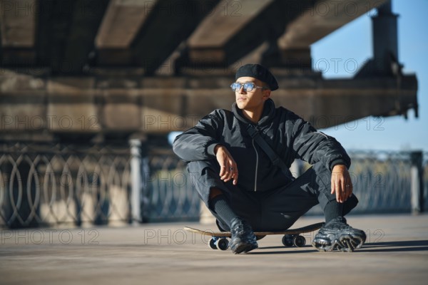 Skater male relax sitting on skateboard on street urban background. Extreme sports concept