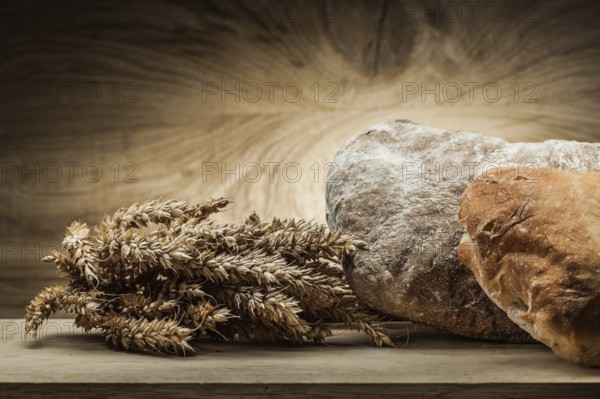Loafs of bread and ears on vintage wood