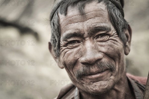 Dolpo, Nepal, circa May 2012: Old wrinkled man with grey hair and moustache smiles nicely to photocamera in Dolpo, Nepal. Documentary editorial, Asia