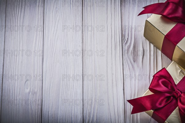 Gift boxes with tied red bows on wooden board copy space holiday concept