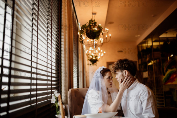 An intimate moment between a bride and groom inside a warmly lit room with chandeliers