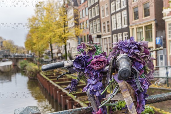 Decorated bicycle with purple flowers on a bridge in an urban environment, Amsterdam, Netherlands