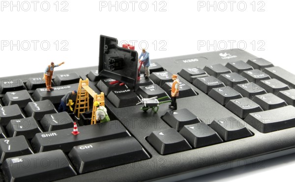 Little world figures repairing the key board of the computer or try to hack or intergate in the system