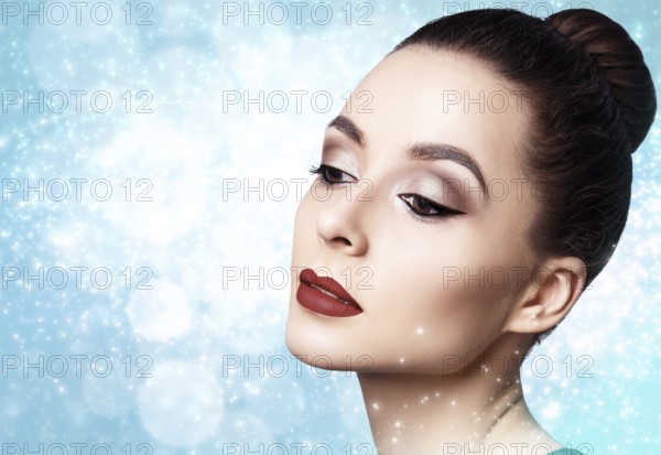 Portrait of young and beautiful woman with evening make-up over winter Christmas background