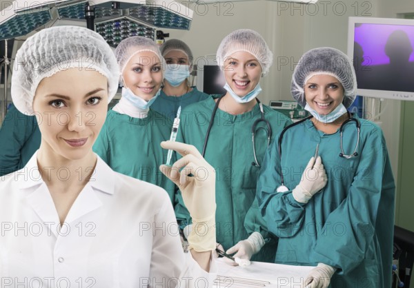Young female anesthetist with syringe on the surgery teem background