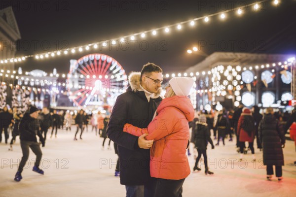 Couple hugging in Saint Valentine's Day. Young romantic couple having fun outdoors in winter. St Valentines Day at city ice rink. New Year holidays. active date ice skating on ice arena on Christmas