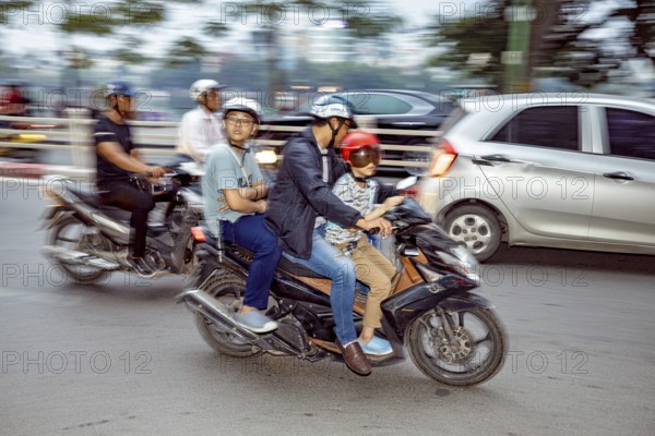 People riding motorbikes in city traffic, wearing helmets, blurred background, The crazy traffic of Hanoi Vietnam