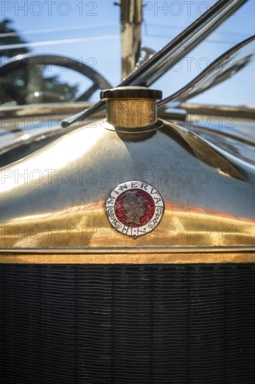 Lisbon, Portugal - Sep 29, 2024: Close-up of Minerva logo grille badge with Roman goddess profile and radiator cap in selective focus on sunny day. Shiny hood cover of Belgian pre-war luxury car, Minerva, Belgium, 1920s, Europe