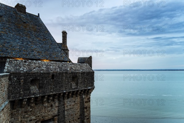 View of the ramparts of Mont Saint Michel with the tide coming in at sunset. Normandy, France, Europe