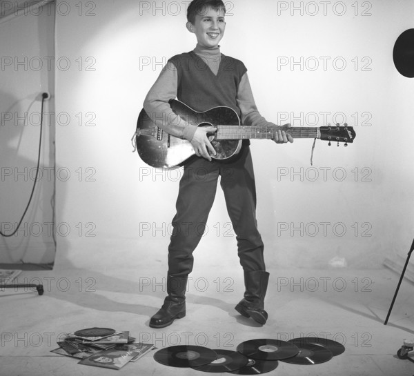 Boy in the 1950s. A boy is photographed in a studio and plays the guitar, perhaps with the Rock n' roll artists of the time in mind. Sweden 1959 Kristoffersson ref CF62
