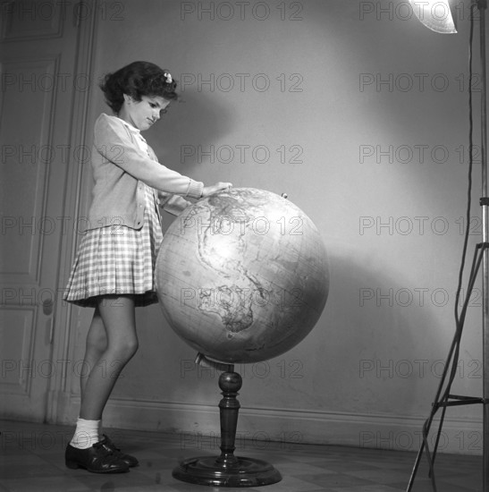 School in the 1940s. A girl in is very closely studying the details of a globe, something is interesting her on the circular map of the world. Sweden 1945 Kristoffersson ref P4-6