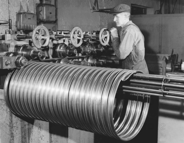 Factory in the 1950s. A worker at the bicycle and motorcycle company Monark in Sweden. The machine is producing steel rims to be used in the production of bicycles . Sweden 1958