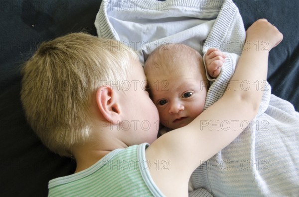 Baby with big eyes beeing cuddled by his older brother, Copenhagen, Denmark, Europe