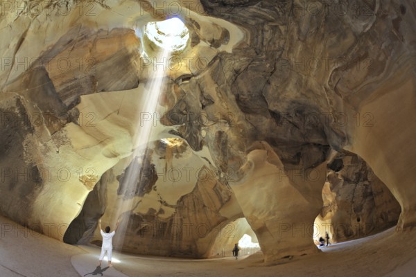 Yoga classes in the cave Beit Guvrin, Israel. Woman in white performs asana Sun salutation