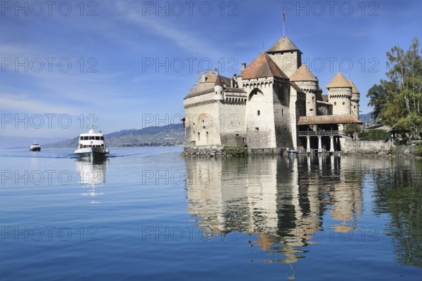 World-wide well-known Château de Chillon on Lake Geneva. The white tourist motor ship floats by a magnificent medieval castle