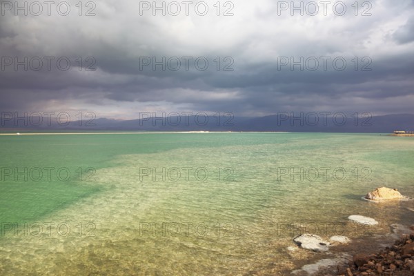 Sunset. Incredible lighting effects in a thunderstorm at the Dead Sea. Multi-colored water in the shallows