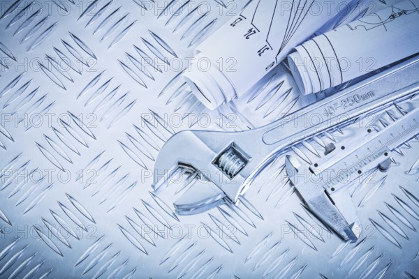 Blueprints vernier caliper adjustable wrench on channeled metal sheet maintenance concept