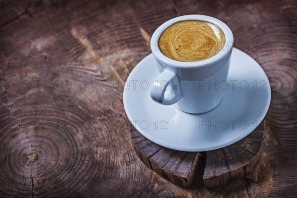 White coffee cup with capuchino on vintage wood cross cutted tree trunk