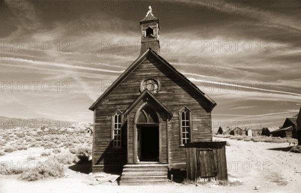 This small chapel made of weather-beaten boards stands on the edge of a dusty road in Bodie. Photo in sepia tone. On the corner of a dusty street in Bodie stands this small chapel constructed of weathered planks. Photo in sepia toning