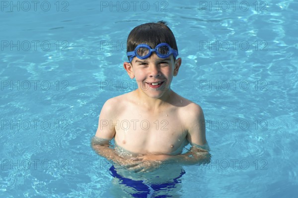 Child in swiming pool. Blue glasses