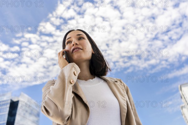 Low-angle view of a woman talking on her cell phone as she looks ahead
