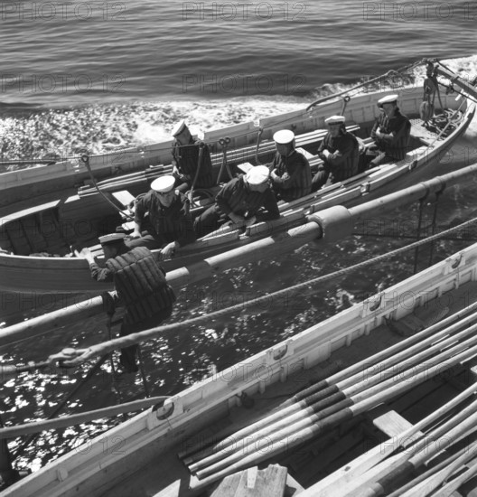 During World war II. The war ship Sverige during navy exercises at sea. The life boat is being fitted and the sailors sit ready to be lowered down in the water. Sweden june 1940. Kristoffersson ref 141
